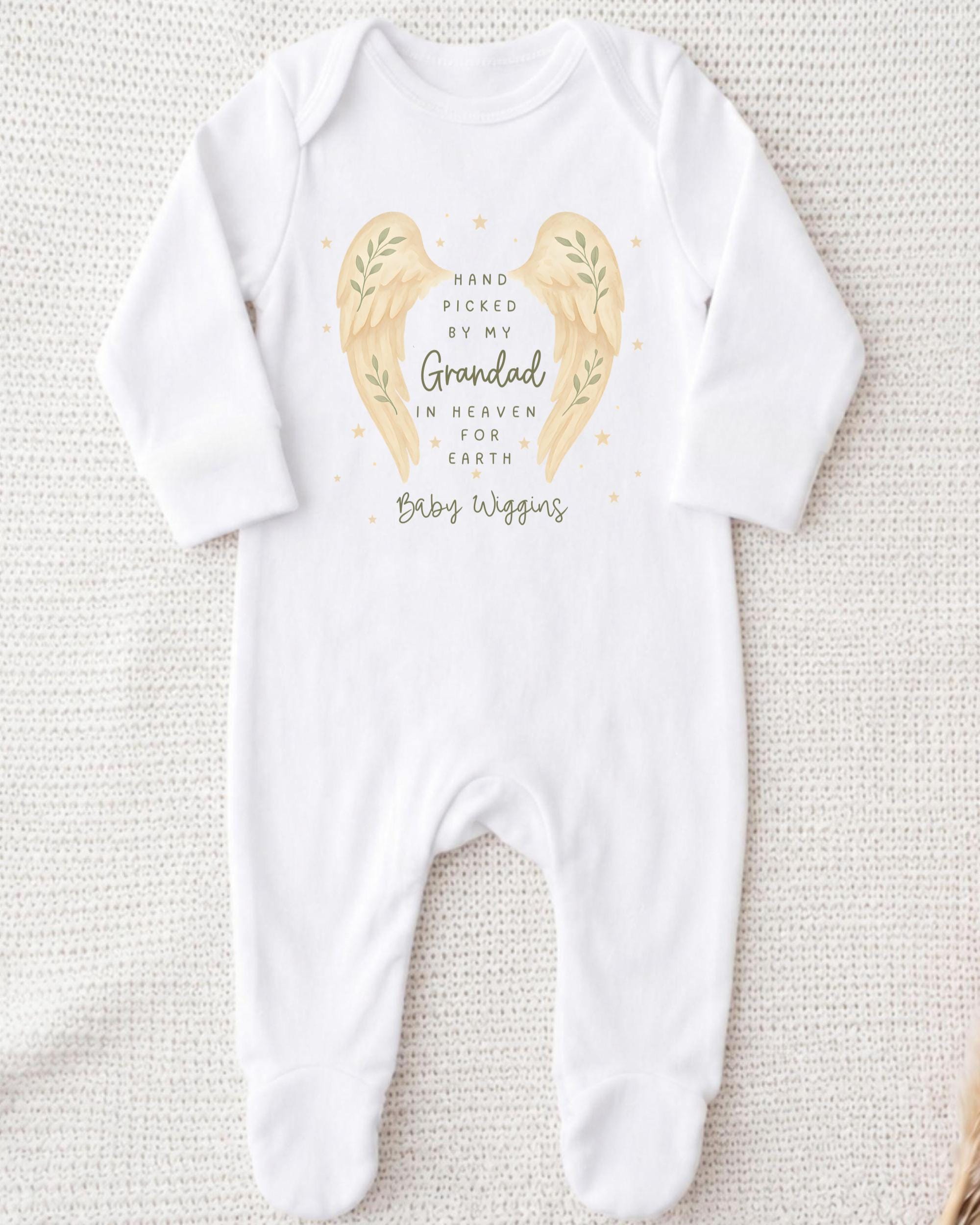 A white onesie with a design of two angel wings and a message about a grandfather in heaven.