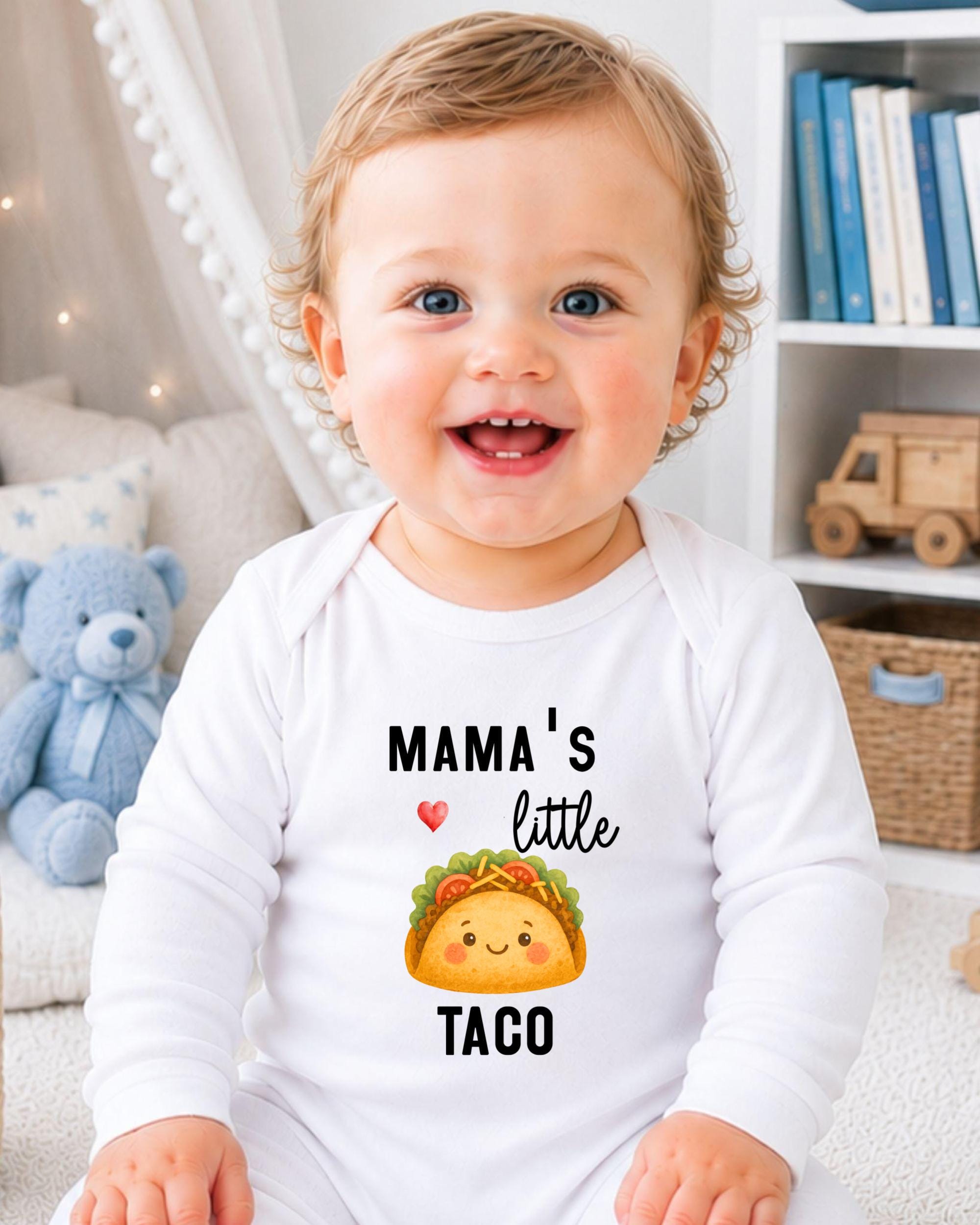 A smiling baby wearing a white onesie with a taco graphic and text that says "Mama's little taco".