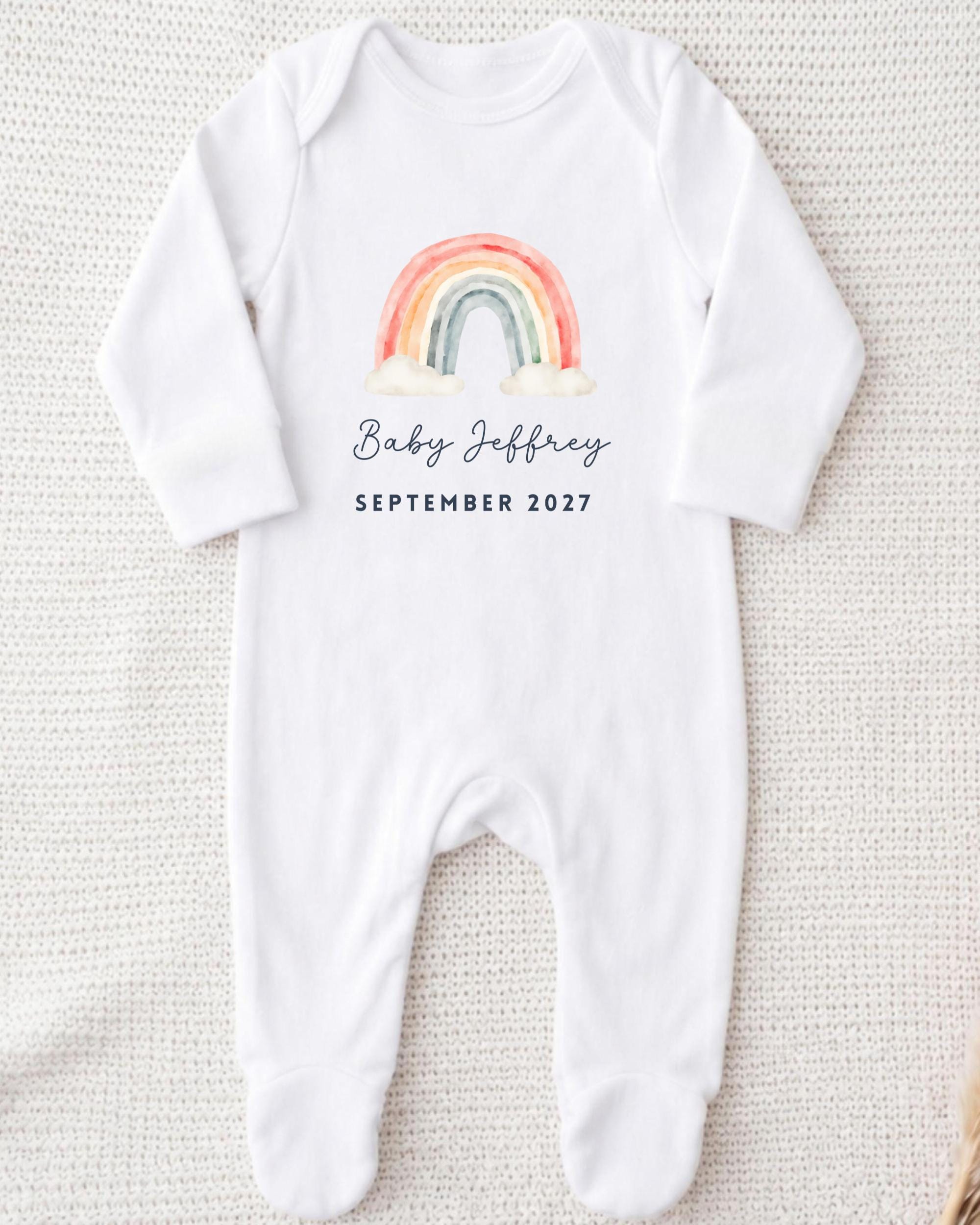 A white onesie with a rainbow graphic and the text "Baby Jeffrey September 2027" printed on it.
