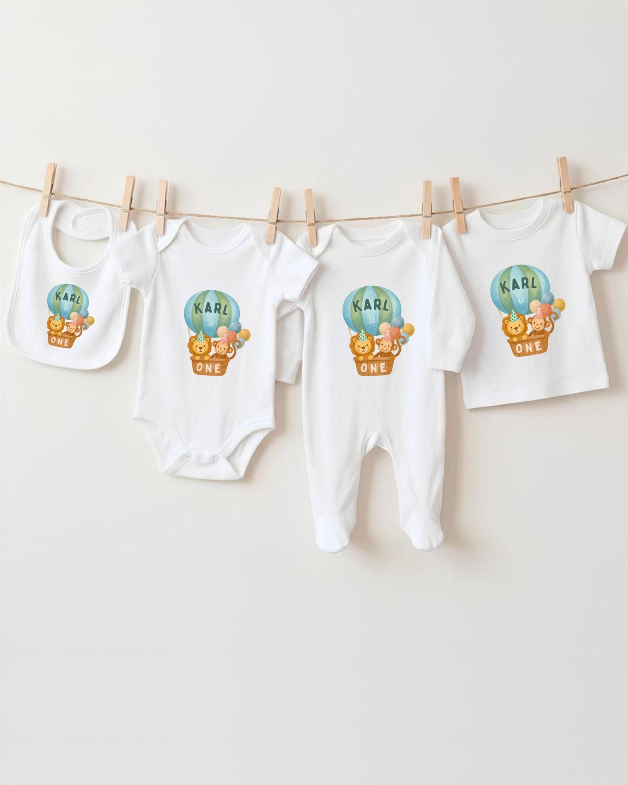 A collection of baby clothes, including onesies and bibs, hanging on a clothesline.