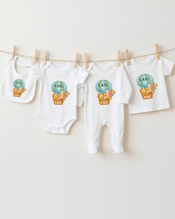 A collection of baby clothes, including onesies and bibs, hanging on a clothesline.