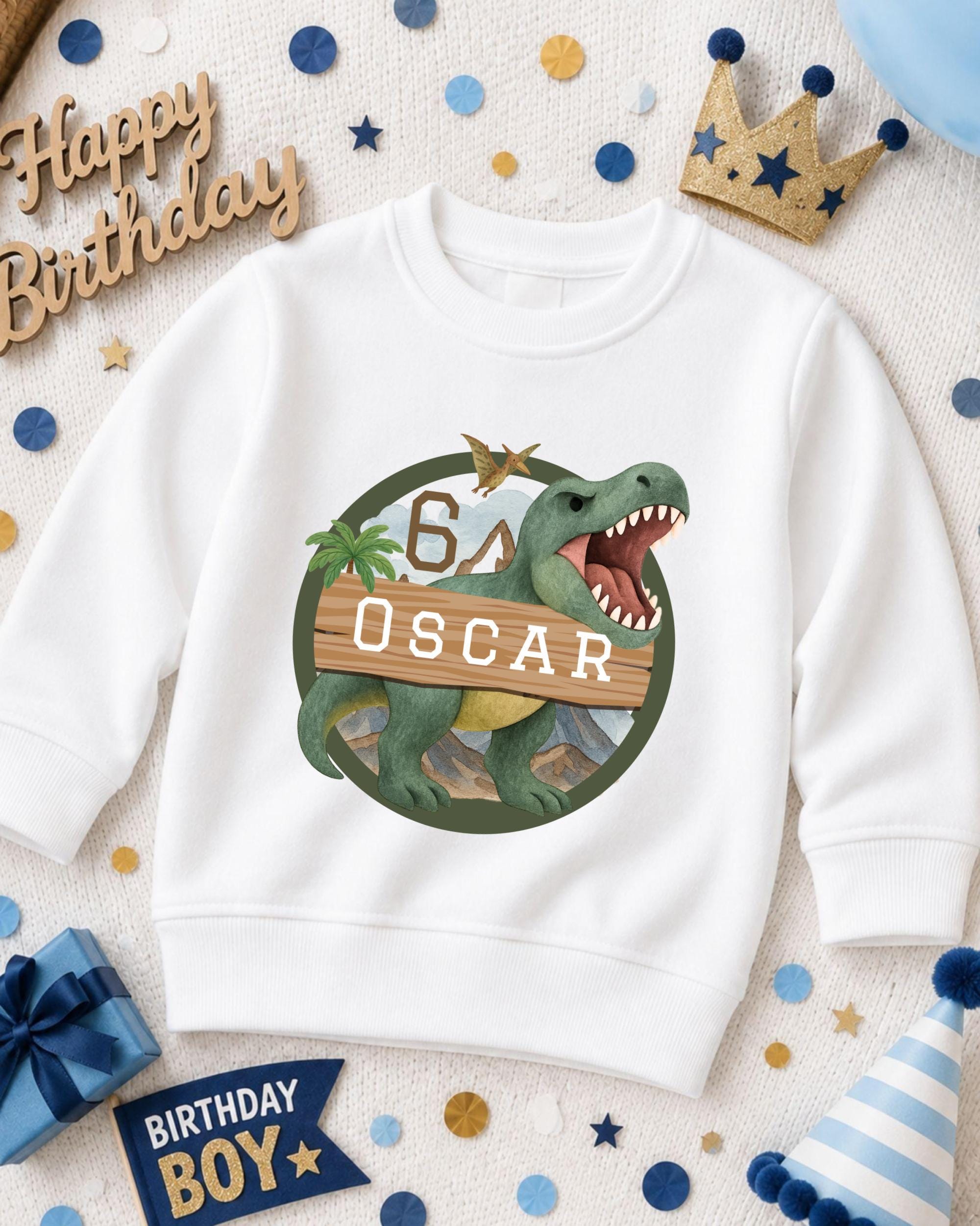A white sweatshirt with a dinosaur graphic and the number 6, along with a birthday hat and other party decorations, suggesting a birthday celebration.
