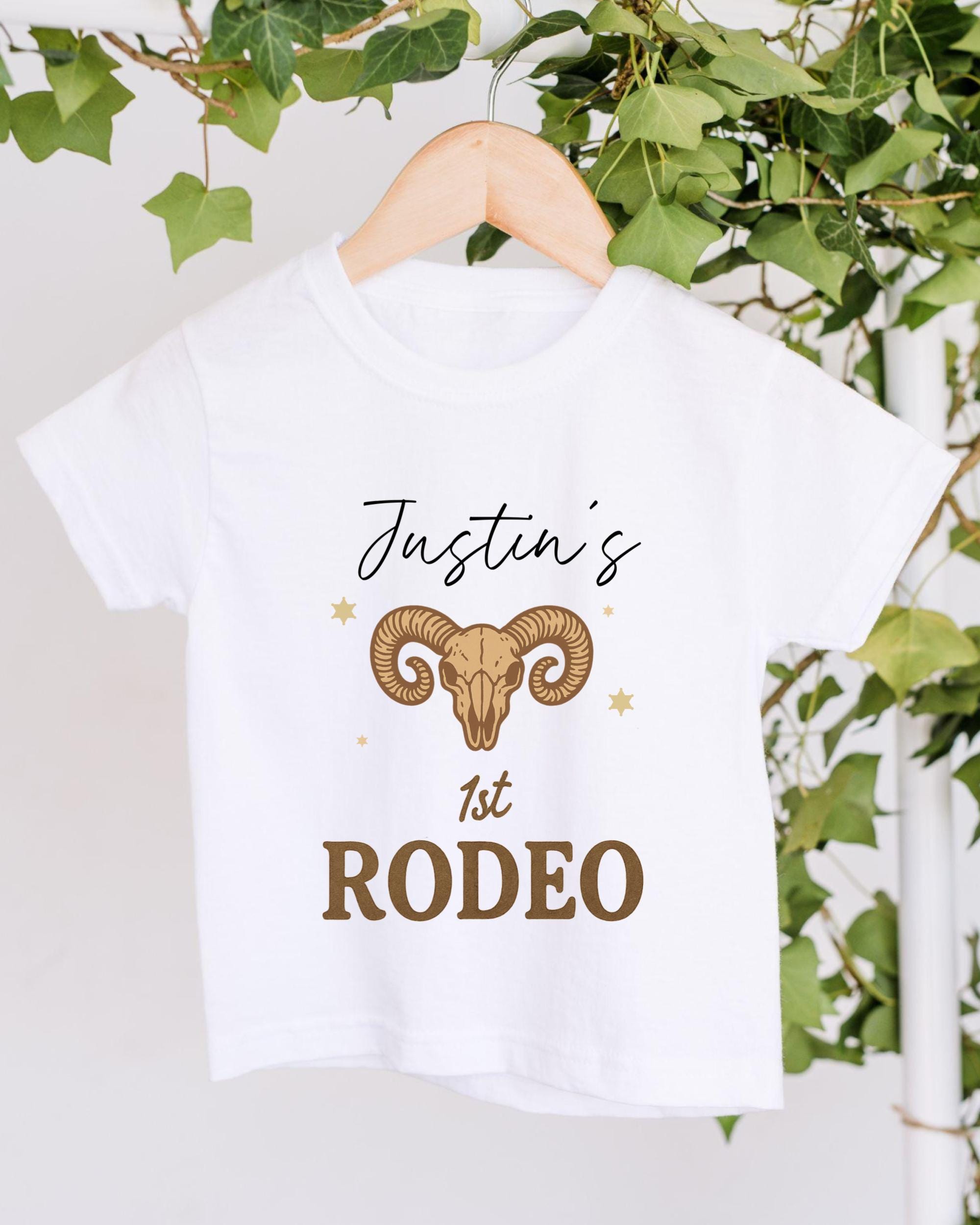 A white t-shirt with a graphic design and text printed on it, hanging on a wooden hanger.