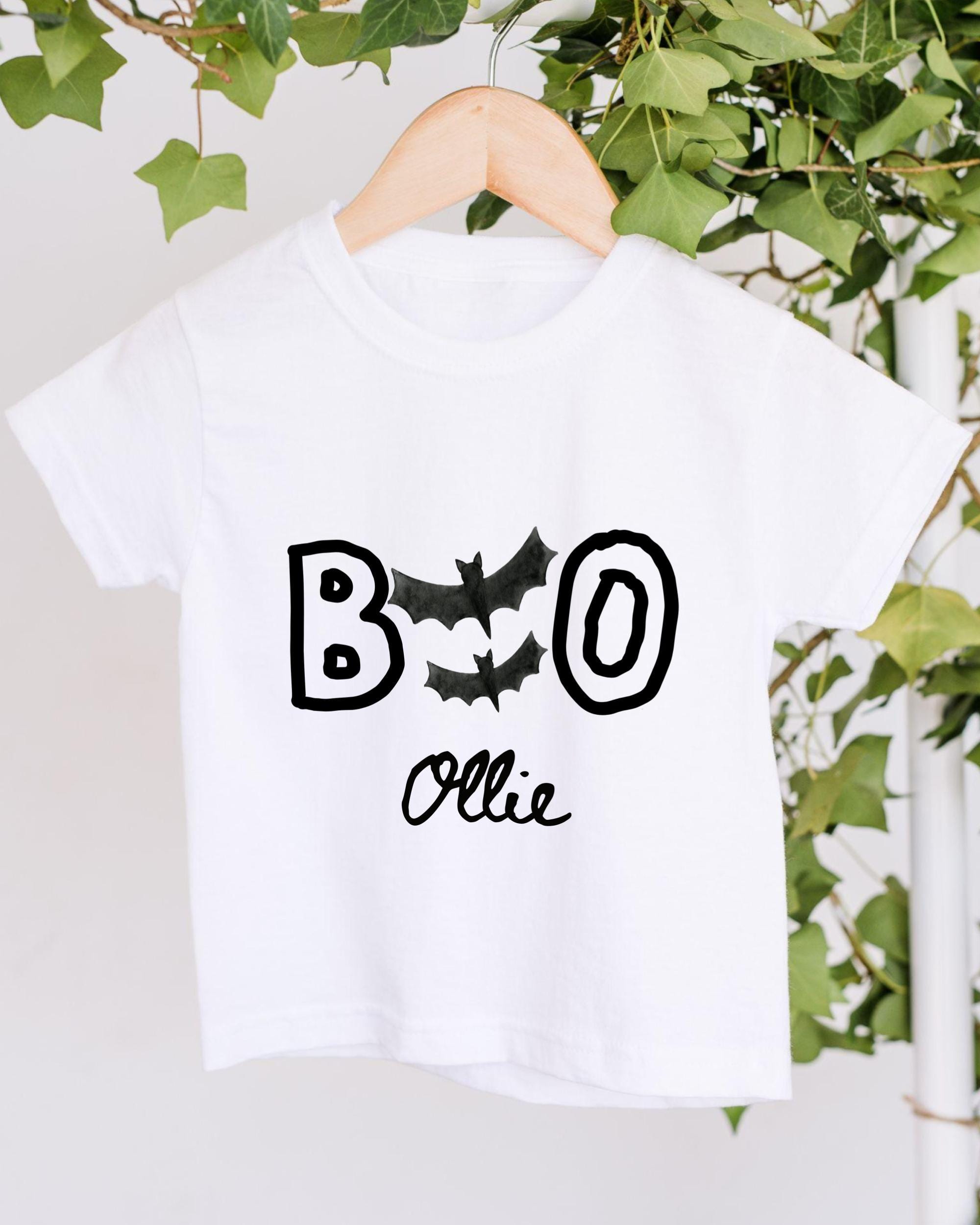 A white t-shirt with the text "BOO OLLIE" printed on it, along with bats and the name "Ollie".