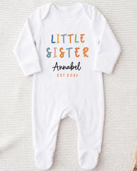 A white onesie with the text "Little Sister Annabel" printed on it.