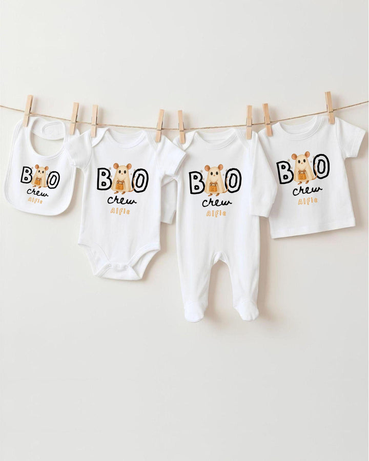 A collection of baby clothes, including bodysuits and bibs, hanging on a clothesline.