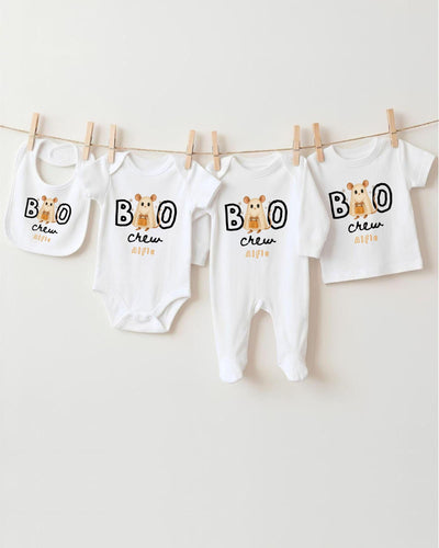 A collection of baby clothes, including bodysuits and bibs, hanging on a clothesline.