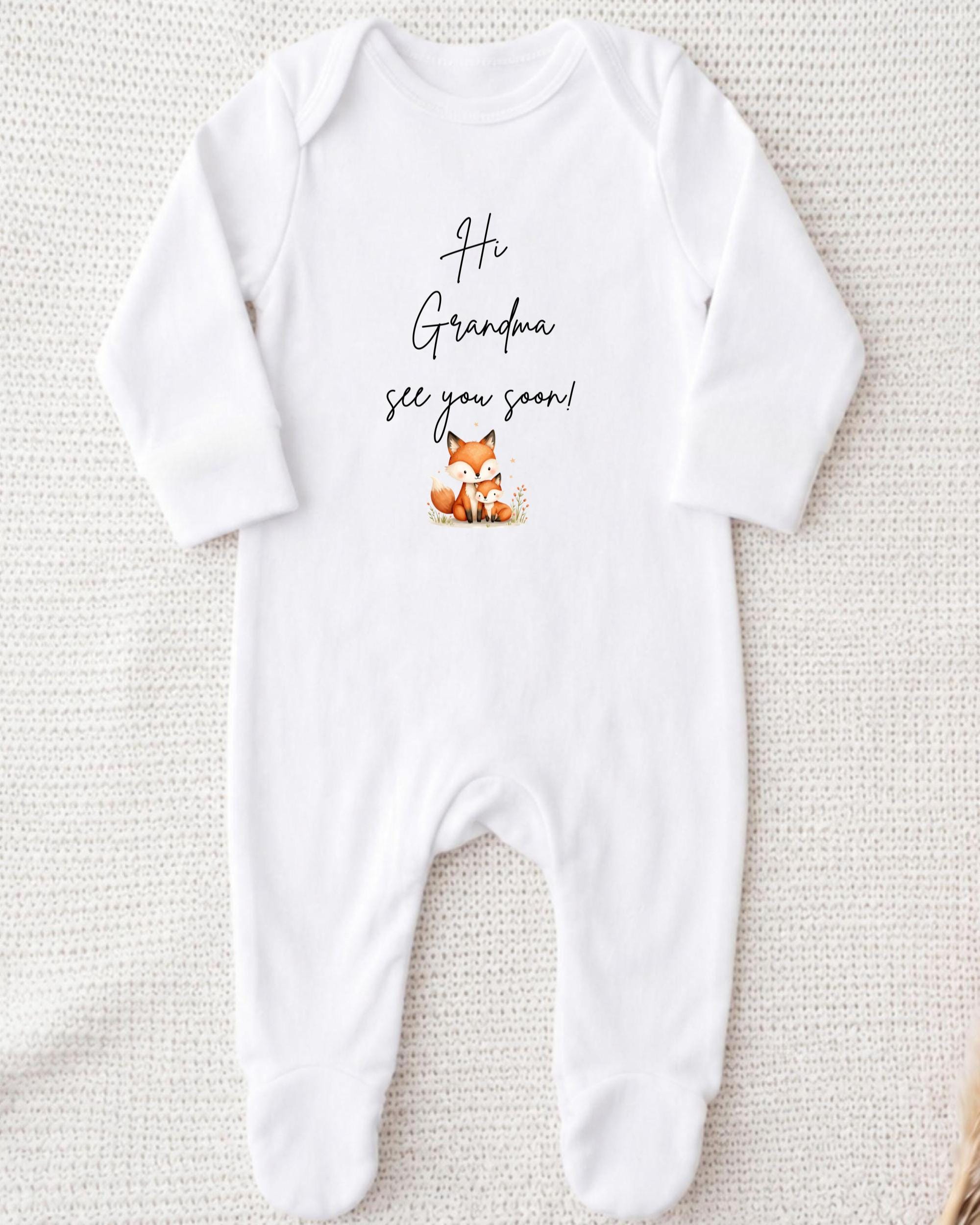 A white onesie with a cute cartoon fox and the text "Hi Grandma, see you soon!" printed on it.