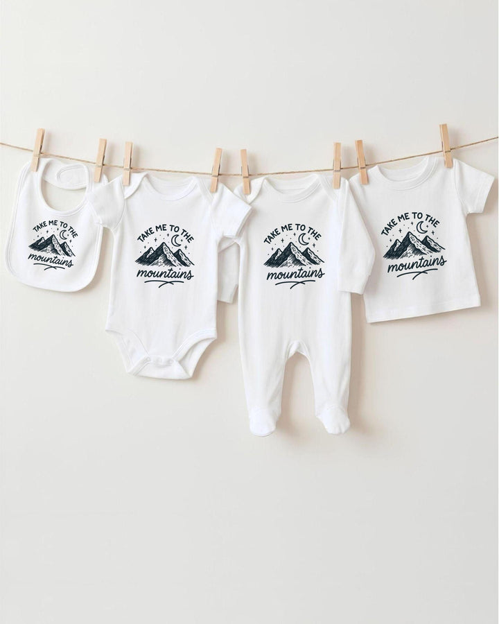 A row of four white baby clothes with mountain designs hanging on a clothesline.