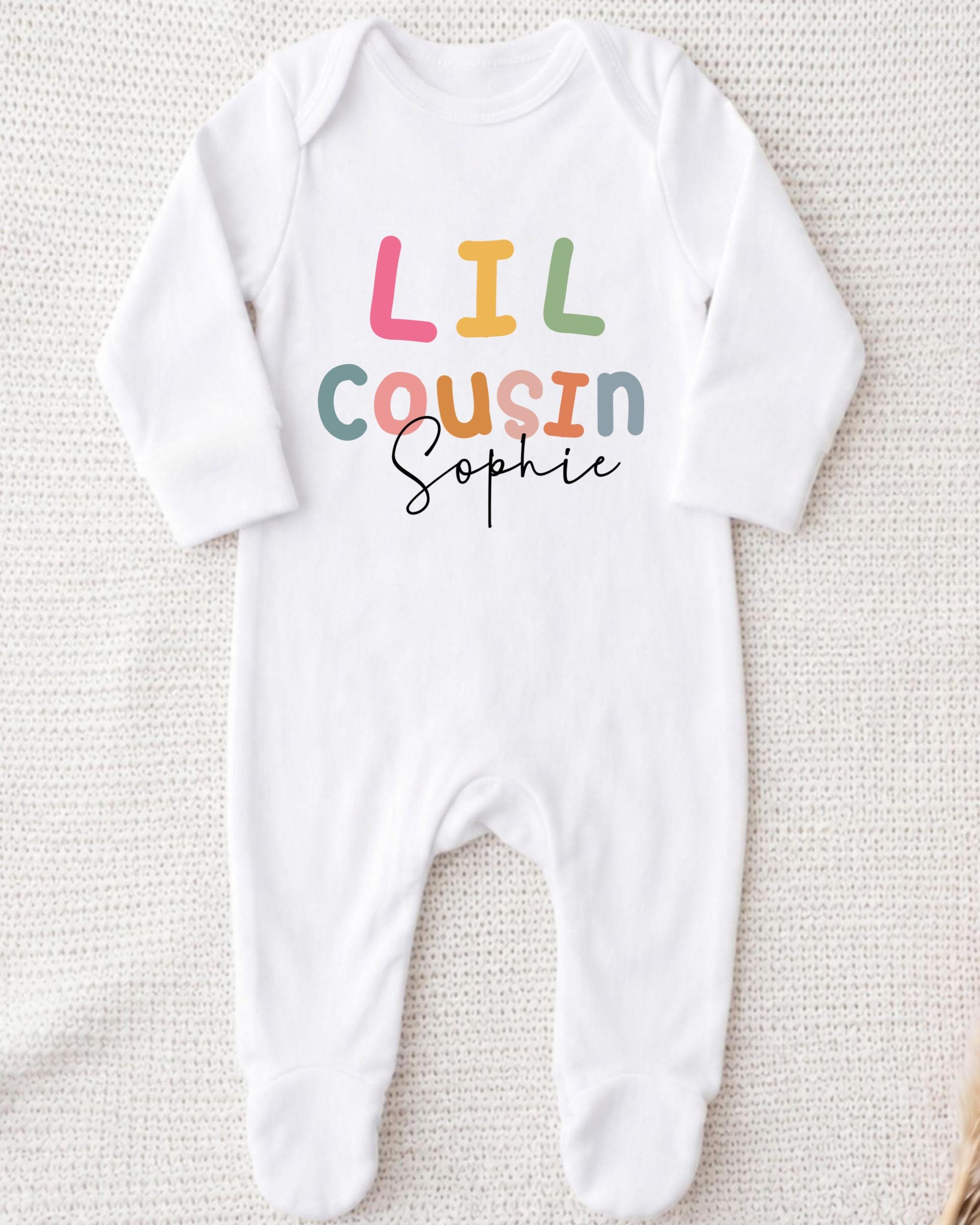 A white onesie with the text "Lil Cousin Sophie" printed on it.