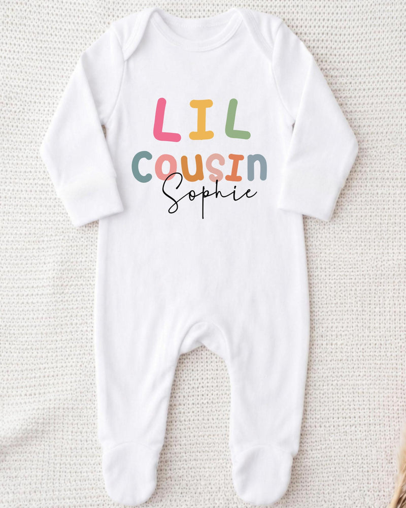 A white bodysuit with the text "Lil Cousin Sophie" printed on it.