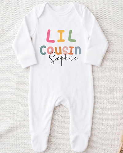 A white bodysuit with the text "Lil Cousin Sophie" printed on it.