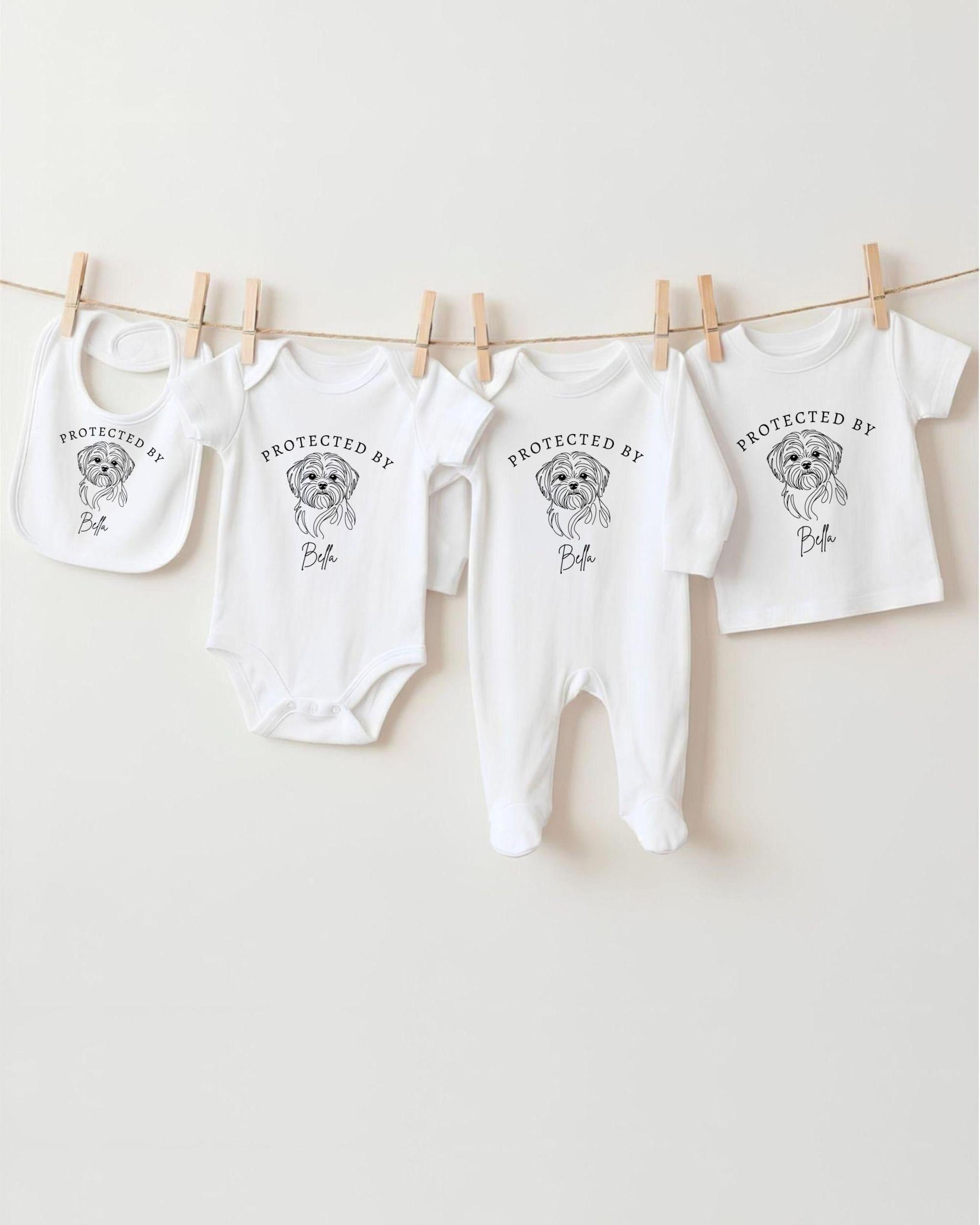 A collection of baby clothes, including onesies and bibs, hanging on a clothesline.