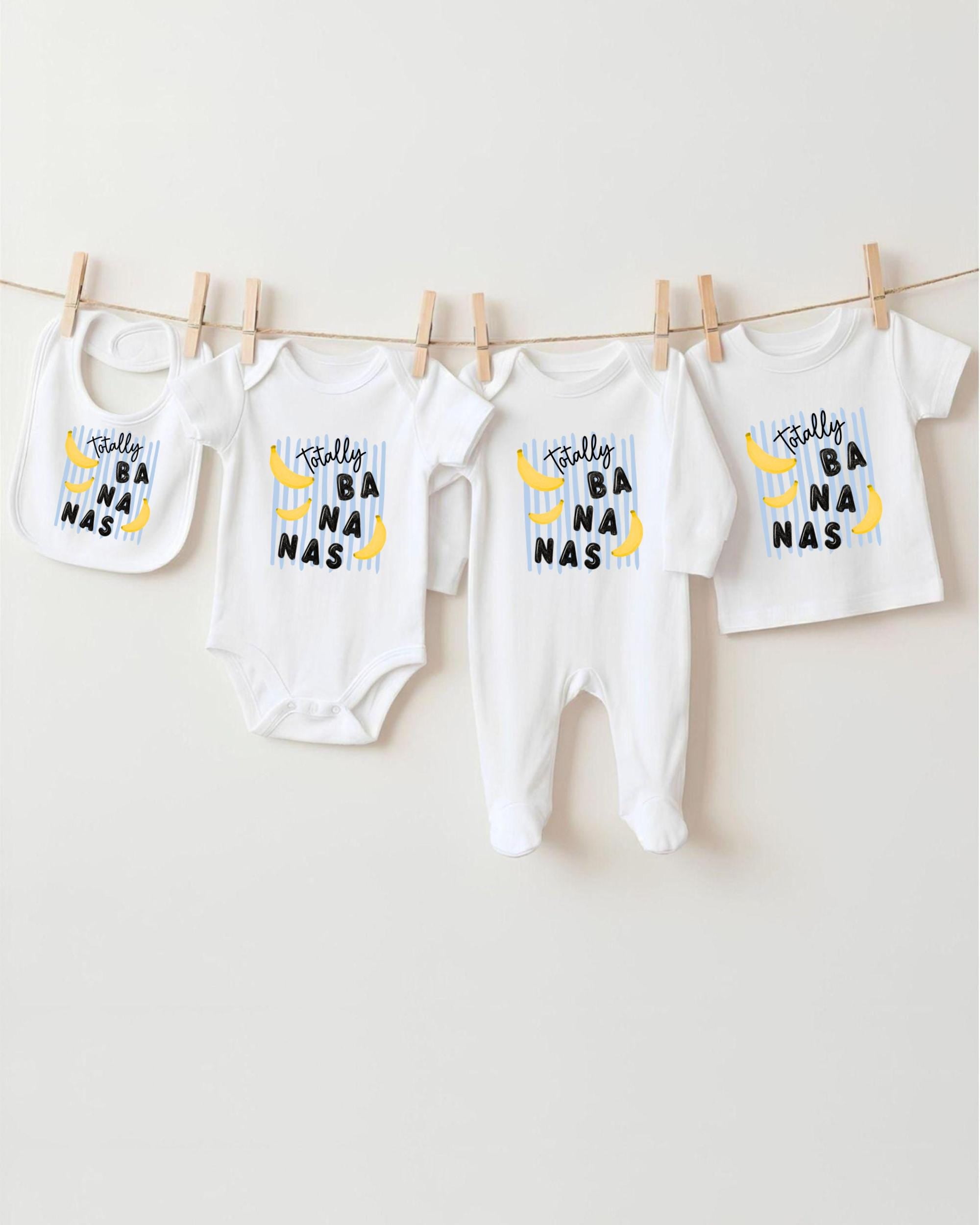 A collection of baby clothes, including onesies and bibs, hanging on a clothesline.