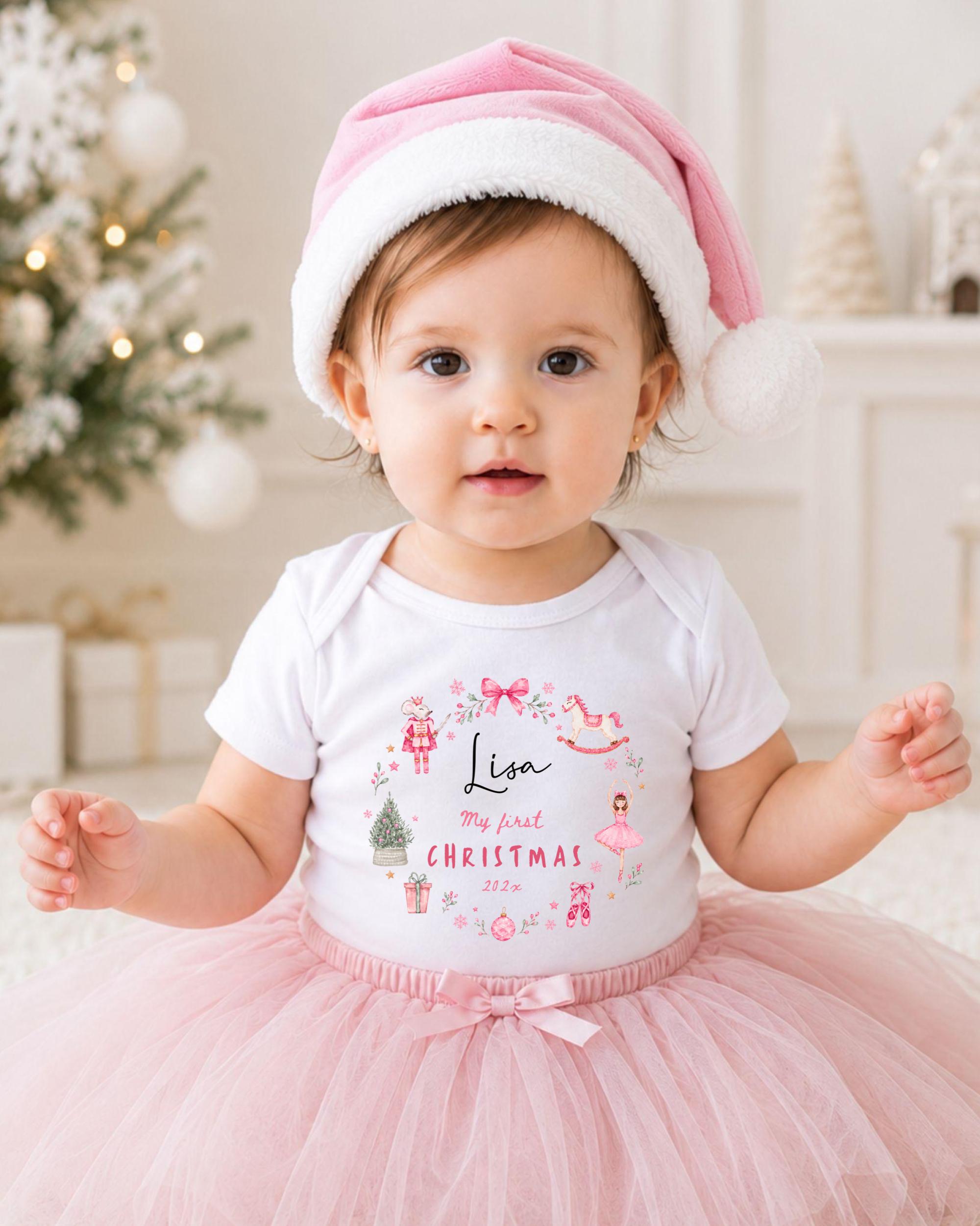 A young girl wearing a pink hat and a white t-shirt with a Christmas-themed design, sitting on a white carpet in front of a Christmas tree.