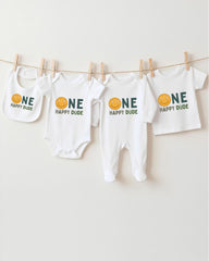 A collection of four white baby clothes with the text "ONE HAPPY DUDE" printed on them, hanging on a clothesline.