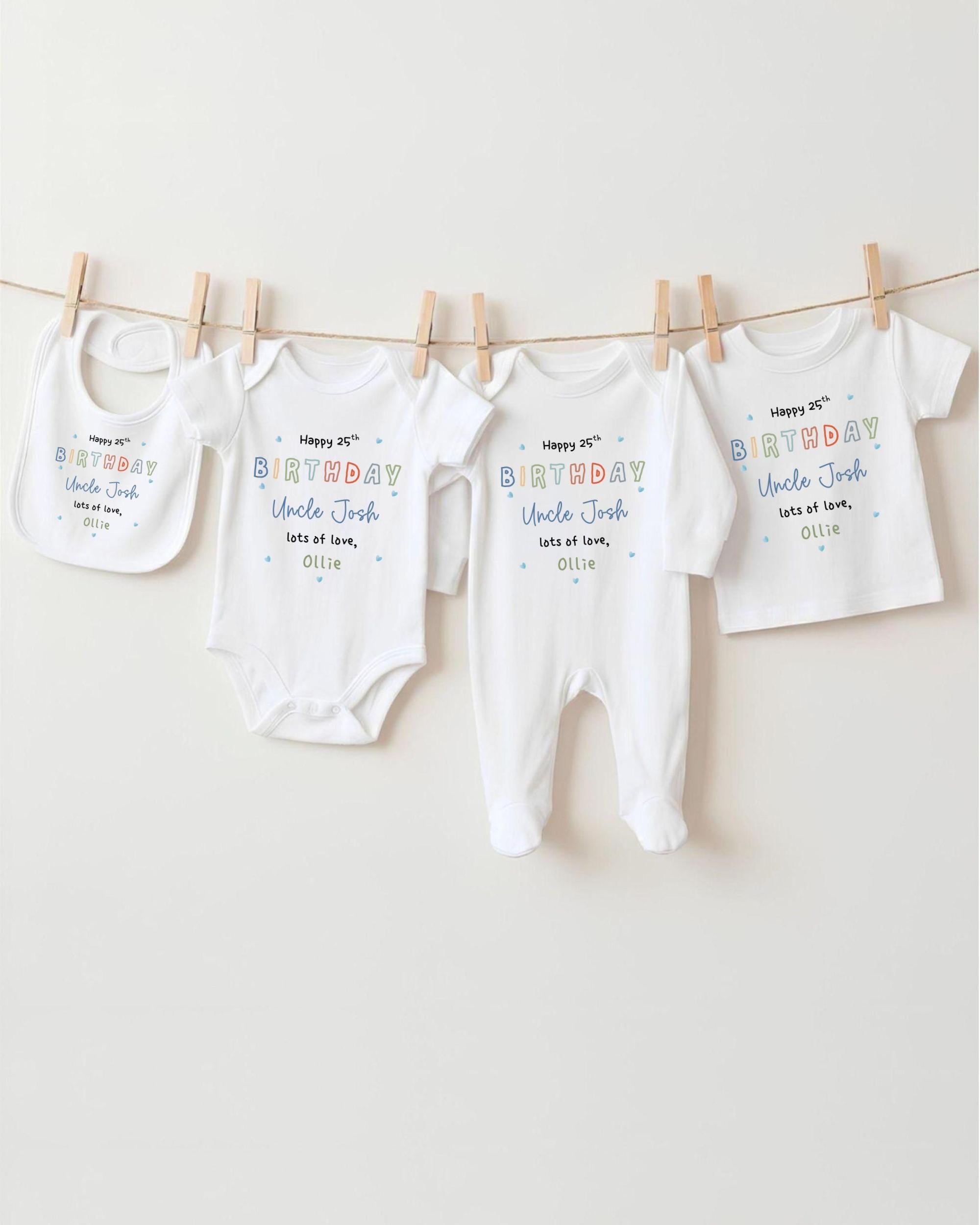A row of four white baby clothes, including onesies and bibs, hanging on a clothesline.