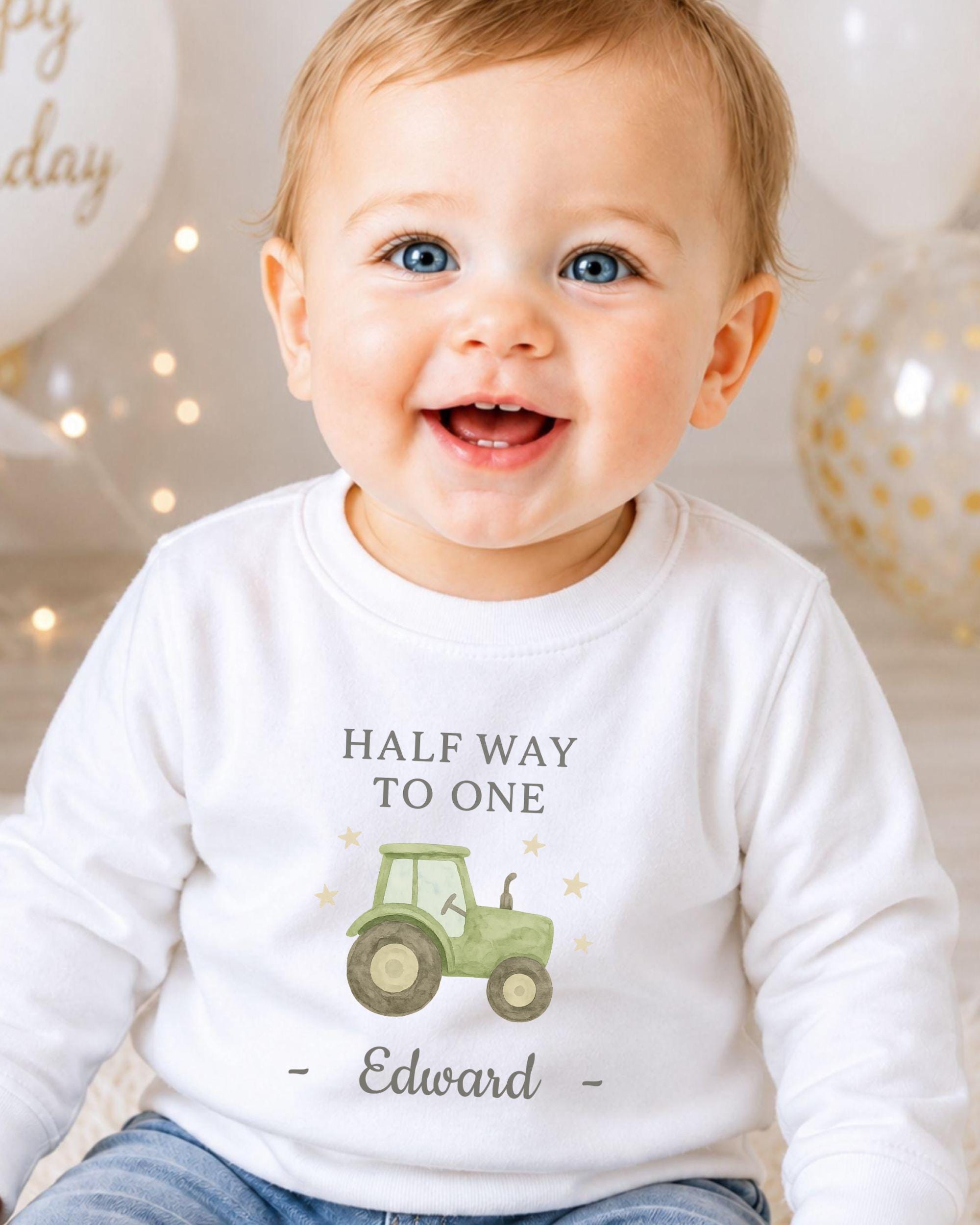 A smiling baby boy wearing a white shirt with a tractor graphic and the text "Half Way to One Edward" printed on it.