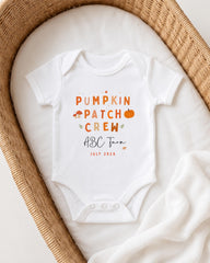 A white onesie with text printed on it, placed in a woven basket.