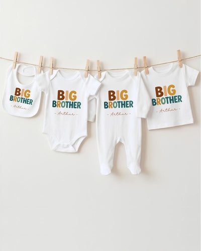 A row of four white baby clothes with the text "BIG BROTHER" printed on them, hanging on a clothesline.
