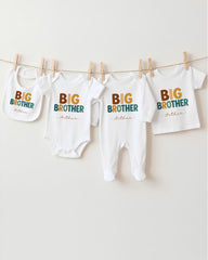 A row of four white baby clothes with the text "BIG BROTHER" printed on them, hanging on a clothesline.