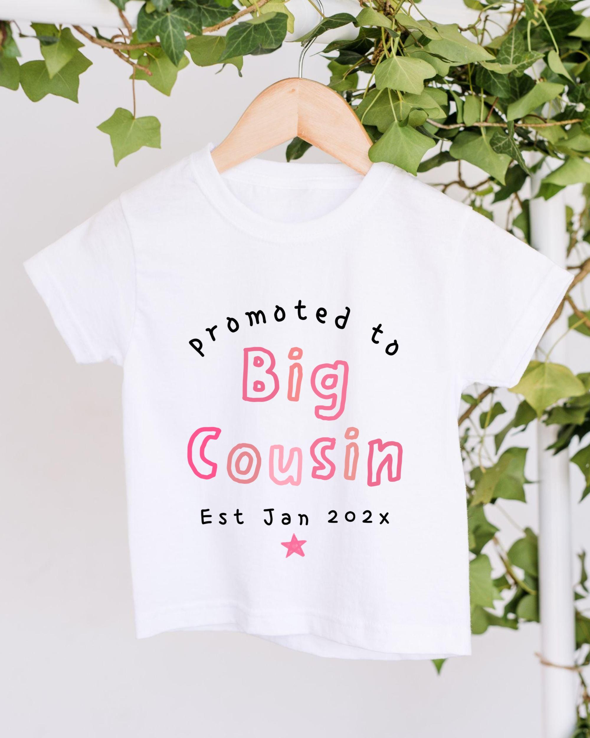 A white t-shirt with text printed on it, hanging on a wooden hanger.