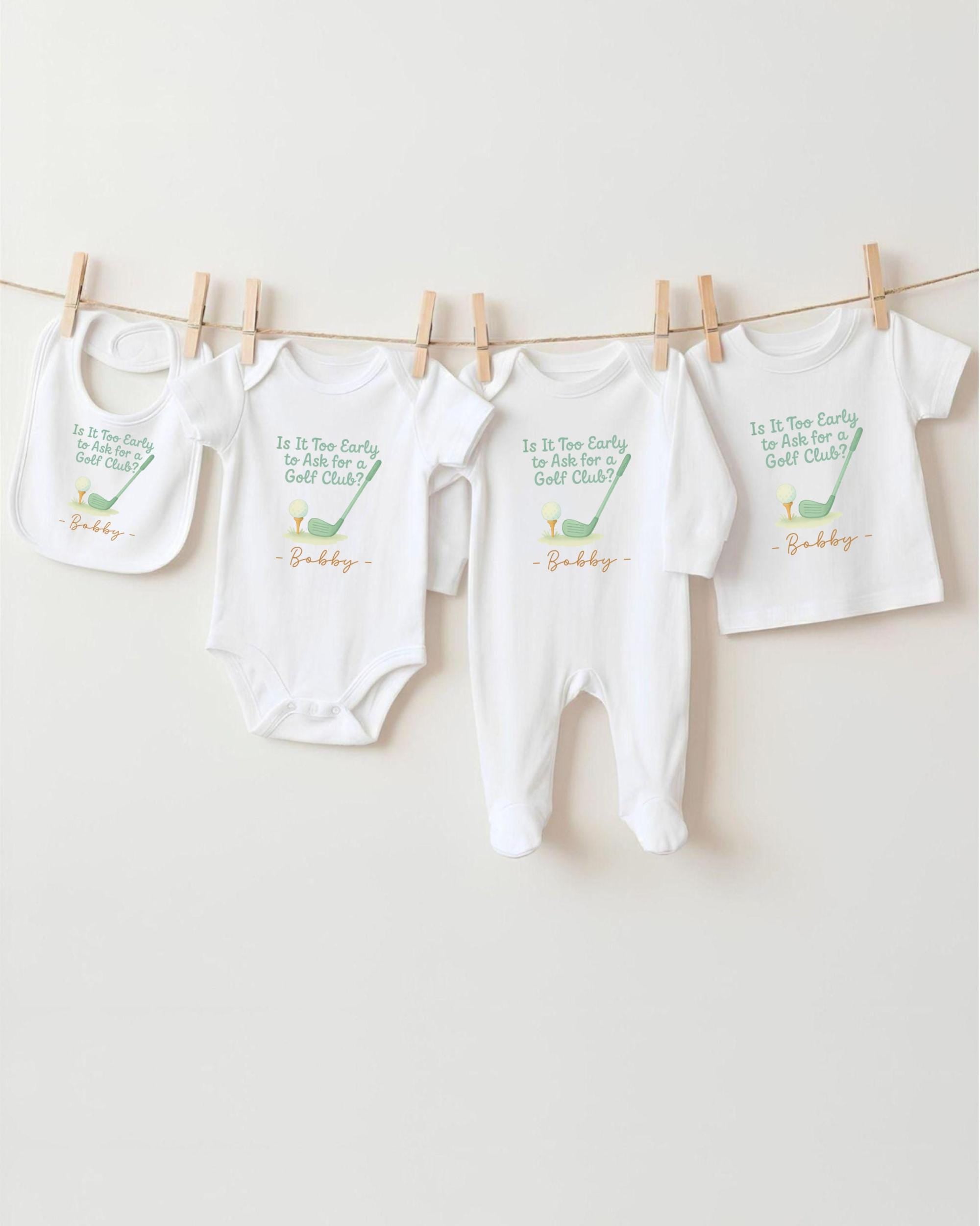 A row of four white baby clothes, including onesies and bibs, hanging on a clothesline.