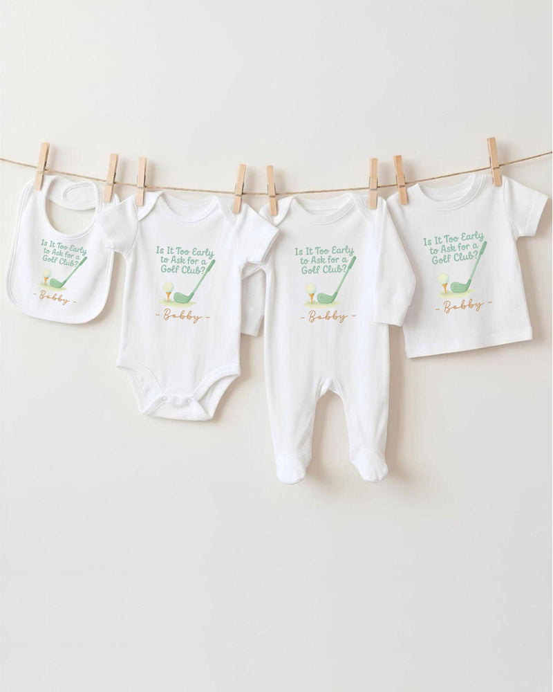 A row of four white baby clothes, including onesies and bibs, hanging on a clothesline.