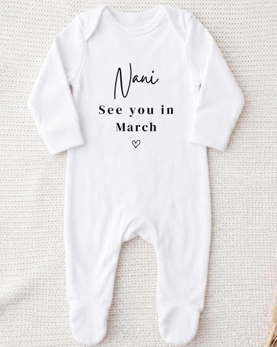 Personalised white Bib with black 'Nani See you in March' lettering and an outline heart for a family pregnancy announcement.