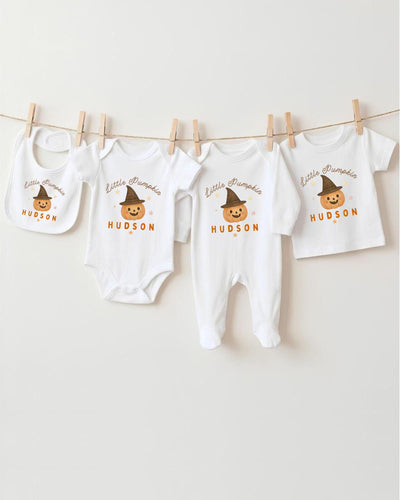 A collection of baby clothes, including bodysuits and bibs, hanging on a clothesline.