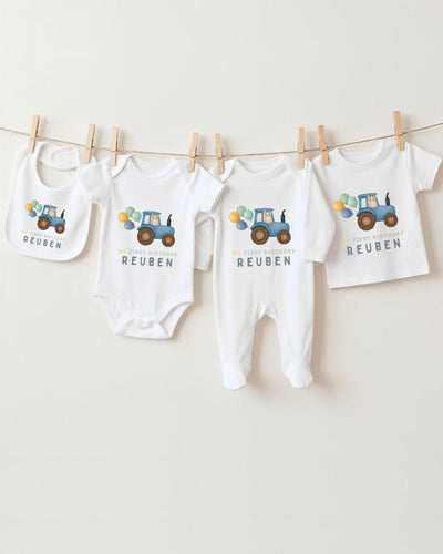 A collection of baby clothes, including bodysuits and bibs, hanging on a clothesline.