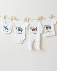 A collection of baby clothes, including onesies and bibs, hanging on a clothesline.
