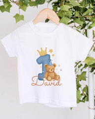 A white t-shirt with a blue number one and a teddy bear wearing a party hat, along with the text "David" printed on it.