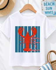 A white t-shirt with a red lobster graphic and the text "Sun, Sea & Lobster" printed on it, hanging on a wooden hanger.