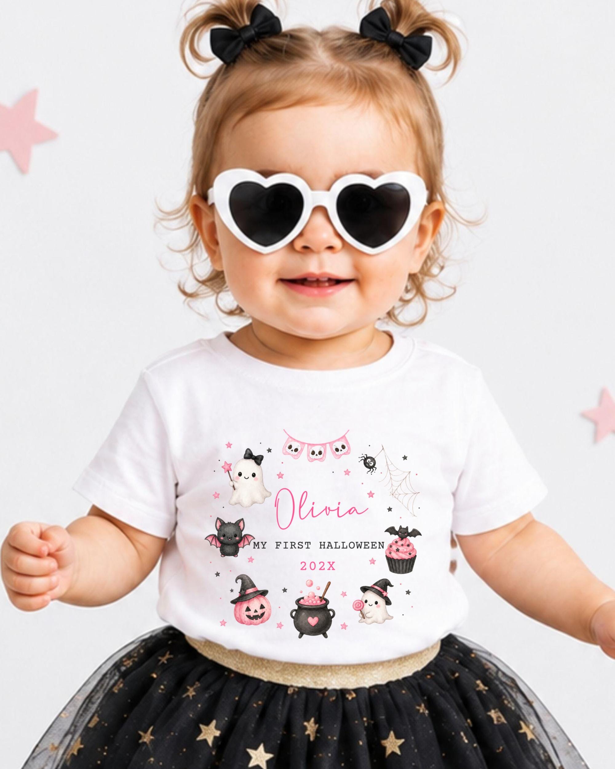 A young girl wearing a white t-shirt with a Halloween-themed design, sunglasses, and a black and gold tutu skirt.