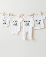 A row of four white baby clothes, including onesies and pajamas, hanging on a clothesline.