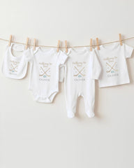 A row of four white baby clothes, including onesies and bibs, hanging on a clothesline.