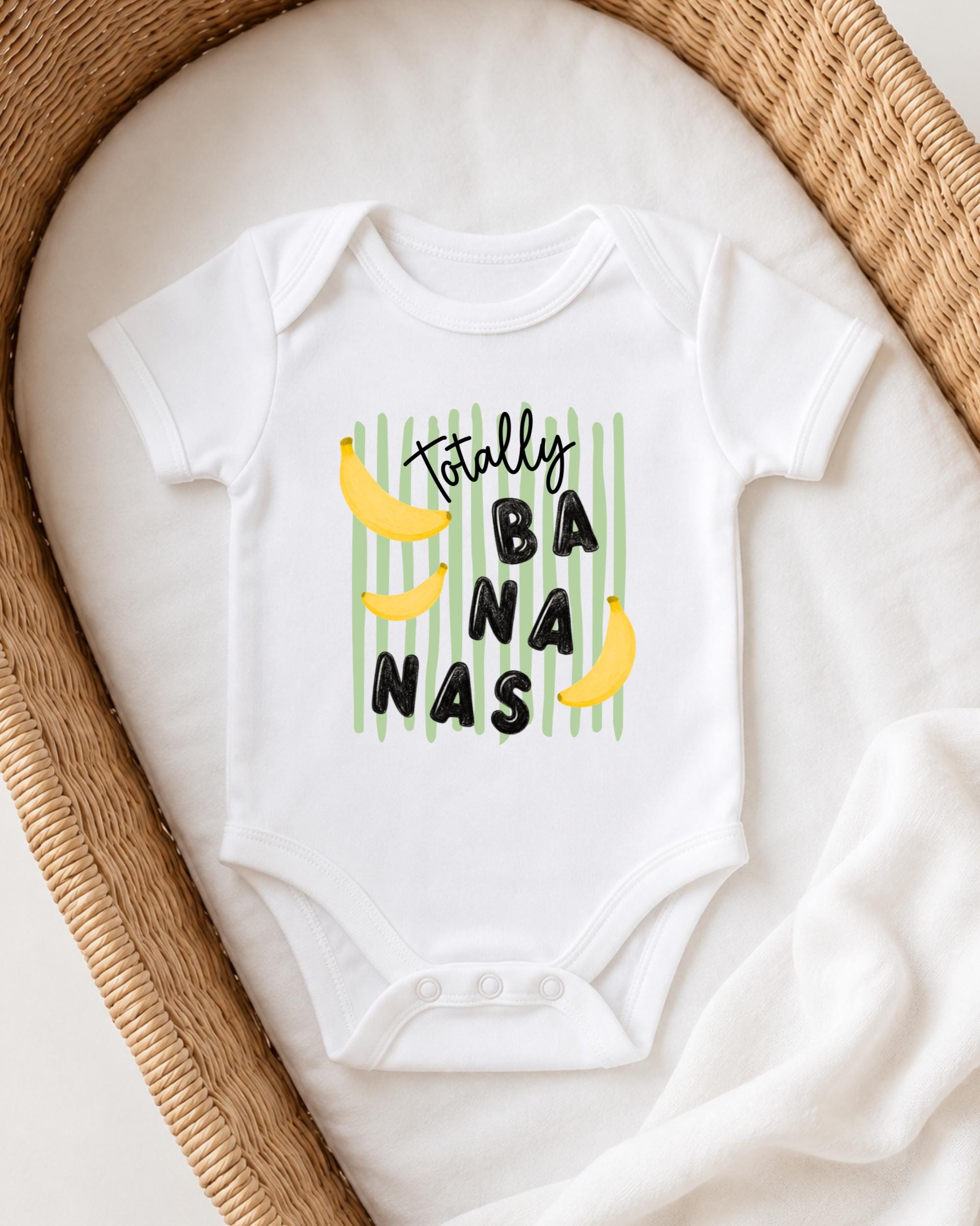 A white onesie with a playful graphic design on it, featuring the text "Totally BANANA NAS" and two yellow bananas.