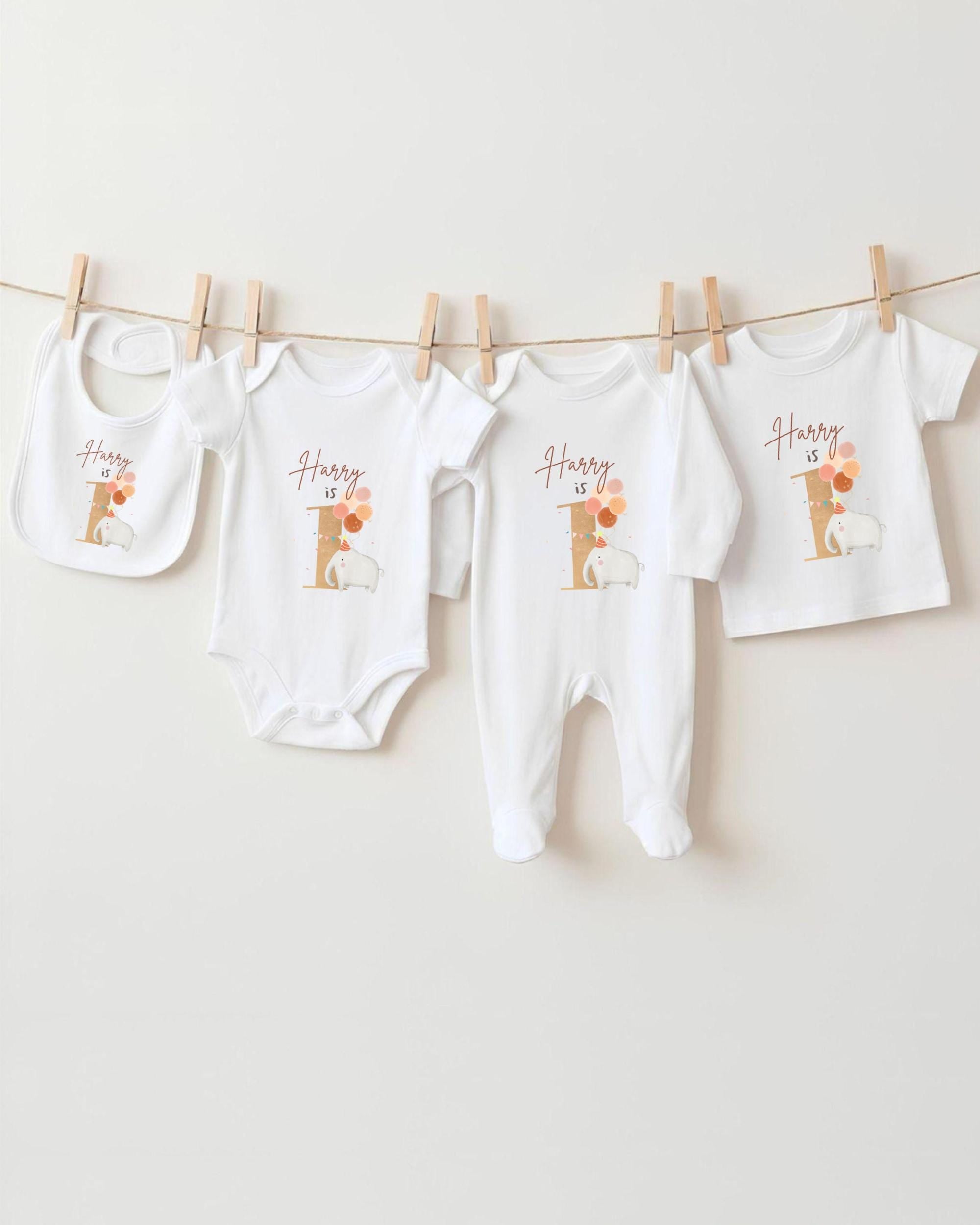 A collection of white baby clothes, including onesies and bibs, hanging on a clothesline.