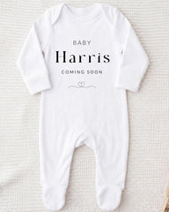 A white onesie with the text "BABY Harris COMING SOON" printed on it.
