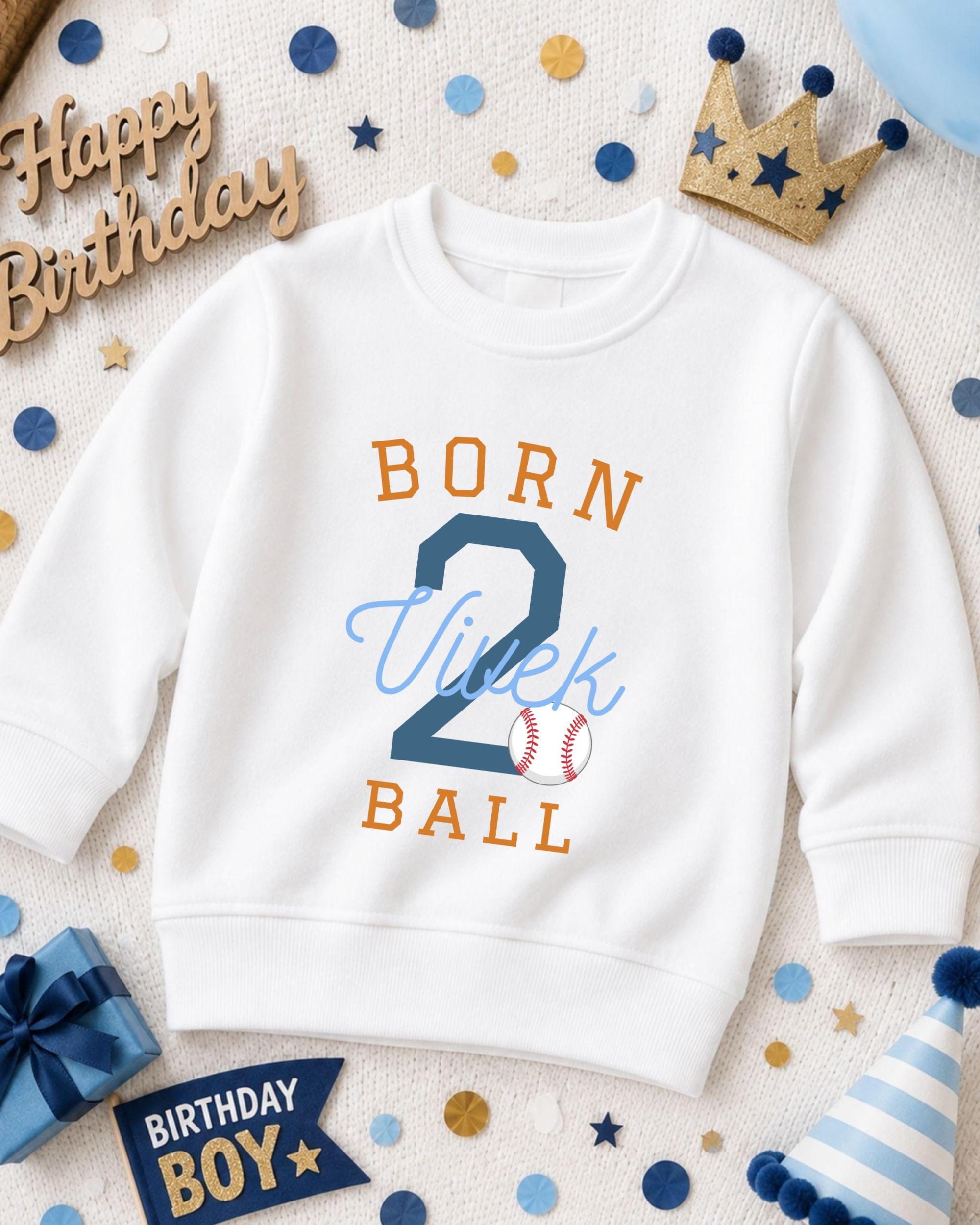 A white sweatshirt with the text "BORN 2 VIEK BALL" printed on it, surrounded by birthday decorations such as a crown, confetti, and a birthday hat.