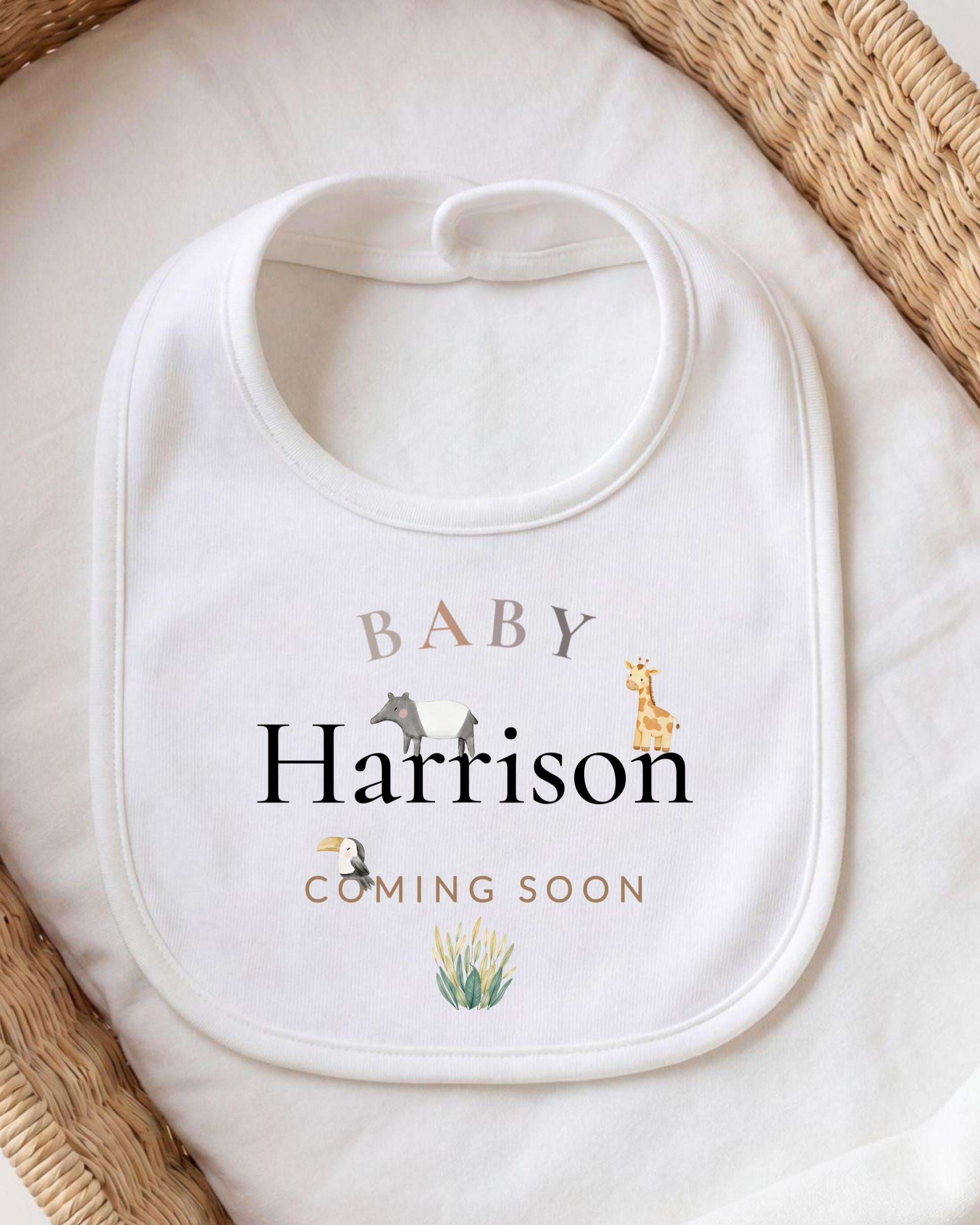 A white baby bib with the text "BABY Harrison" printed on it, along with illustrations of animals.