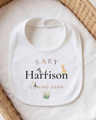 A white baby bib with the text "BABY Harrison" printed on it, along with illustrations of animals.