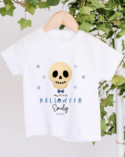 A white t-shirt with a skull design and text printed on it, hanging on a wooden hanger.