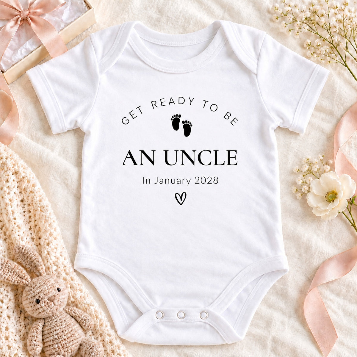 Square pregnancy announcement image of a white Get Ready to Be an Uncle Baby Vest with January 2028 wording, cream gift box, beige ribbon and coffee cup.
