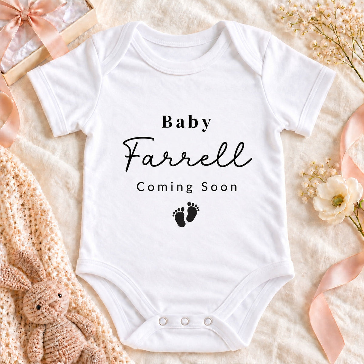 Square pregnancy announcement image of a white Baby Farrell Coming Soon Baby Vest with footprints, cream gift box, beige ribbon and ultrasound photograph on neutral linen.