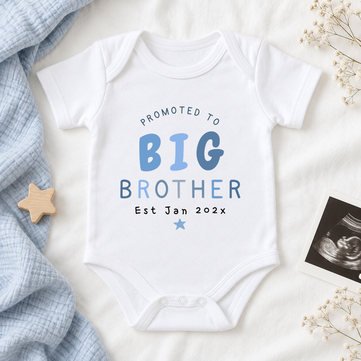 White Promoted to Big Brother Baby Vest personalised with Est Jan 202x, styled with pale blue muslin, a wooden star and an ultrasound scan photograph.